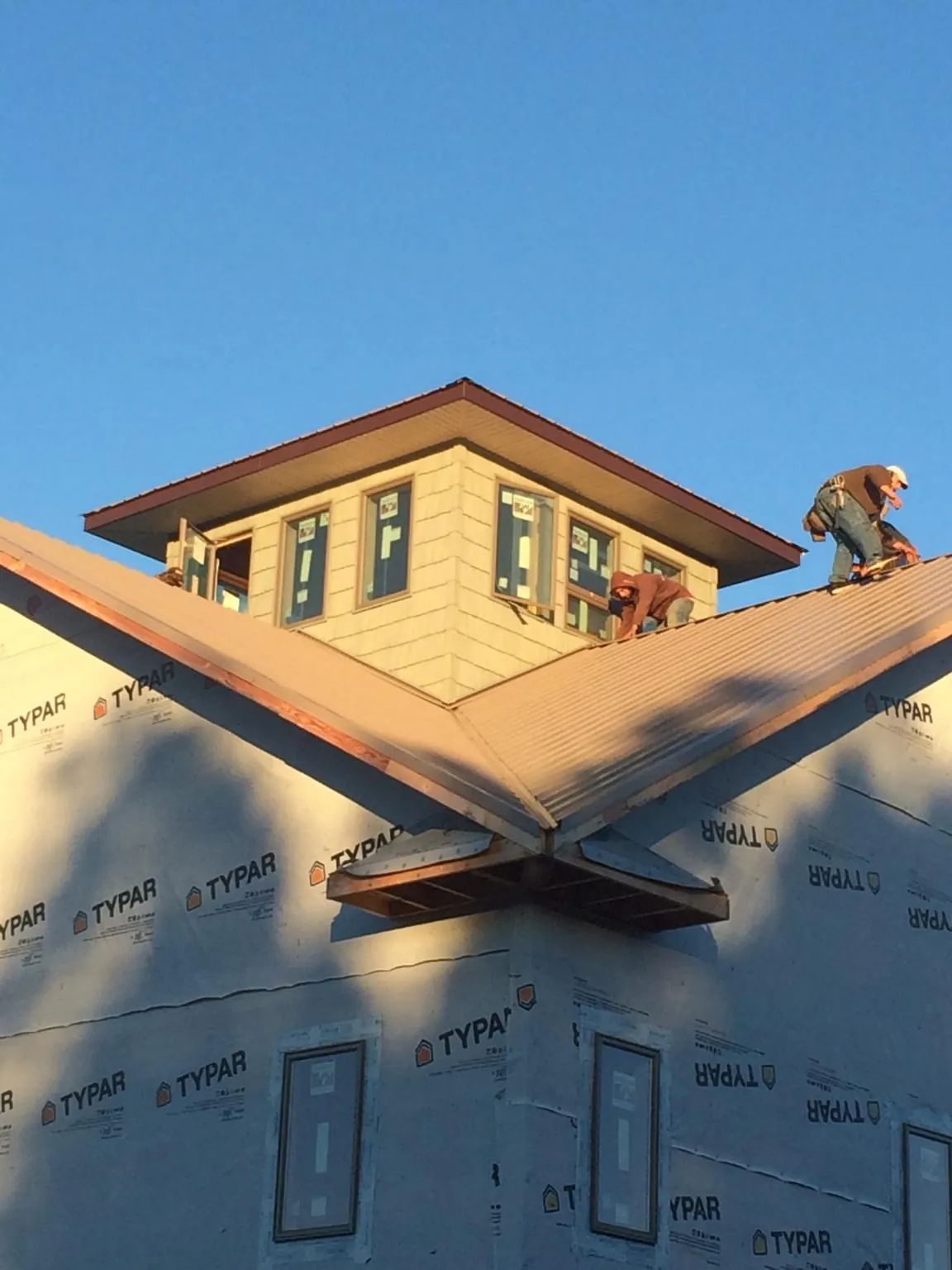 Roofers working around a rooftop cupola on a new metal roof at sunset — Roof Waterproofing in Woodburn by Roofing Brothers